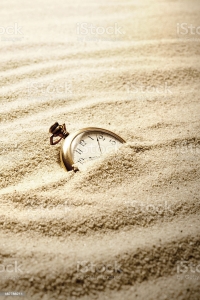 Antique Gold Watch Partially Buried in Sand. Focus on watch.